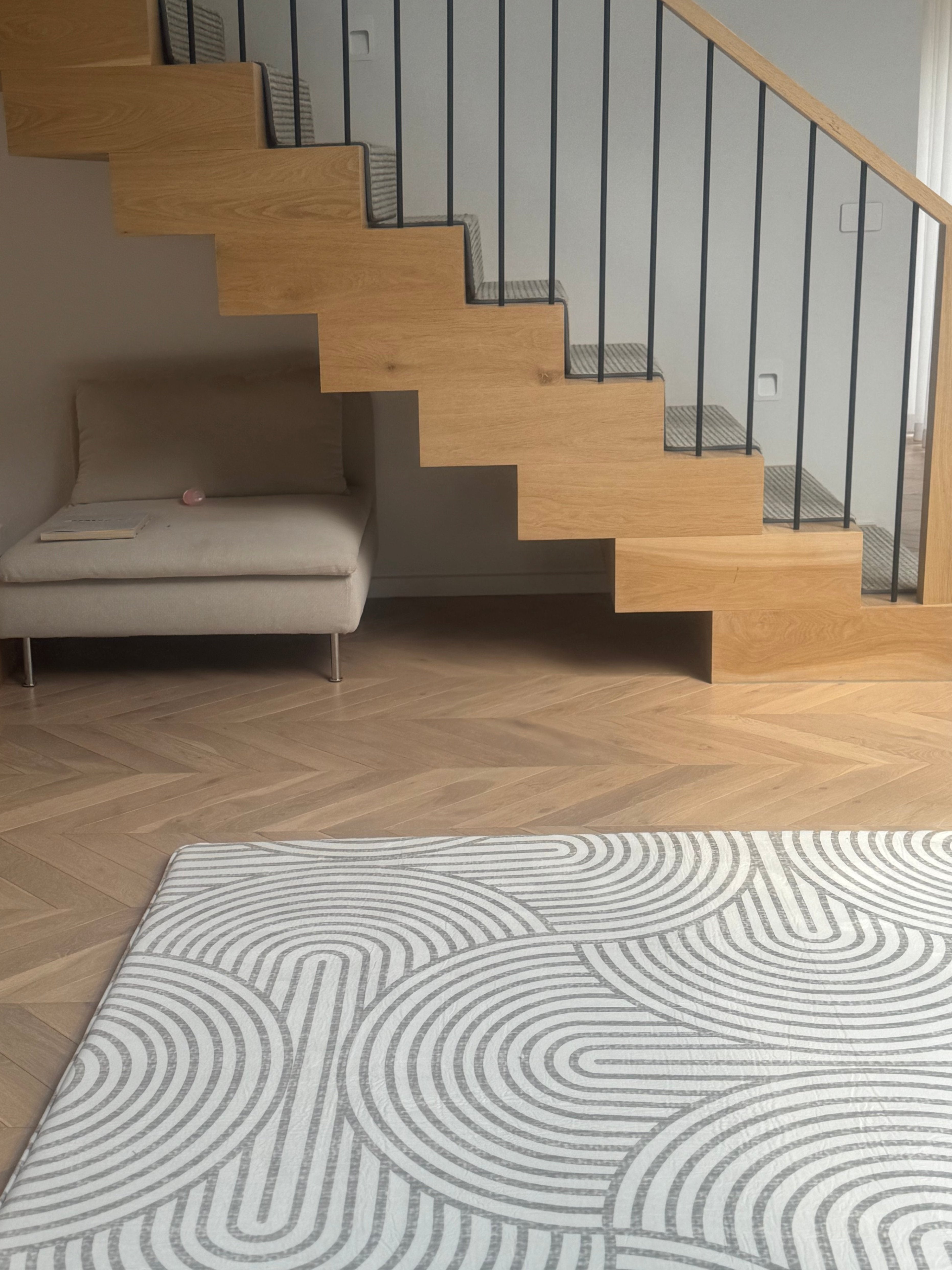 A white rug positioned before a staircase, adding comfort and style to the space.