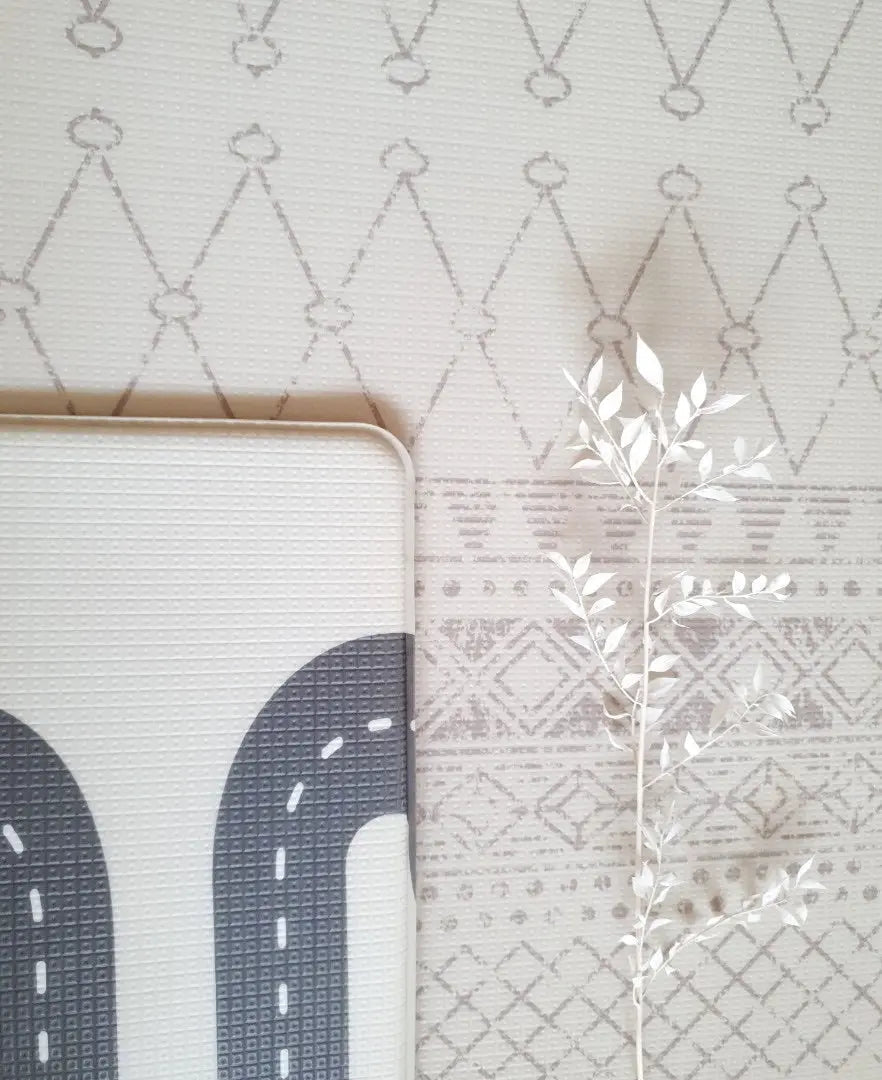 Playmat folded over showing two sided design. Side A has a neutral boho pattern and side B has a track design.