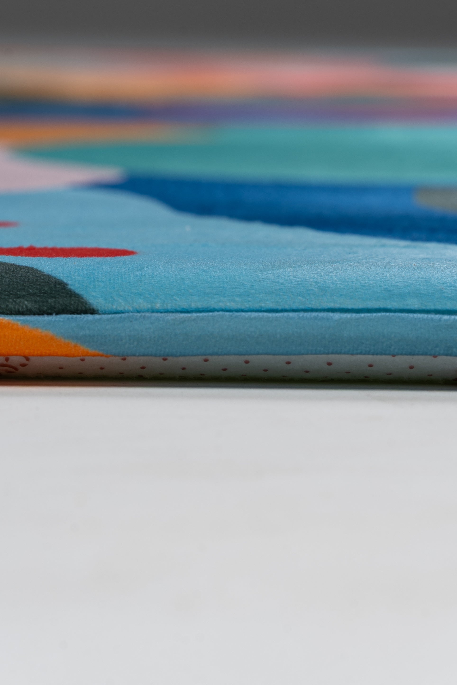 A lively rug in a living room, complemented by a couch and a window, adds color and comfort to the setting.